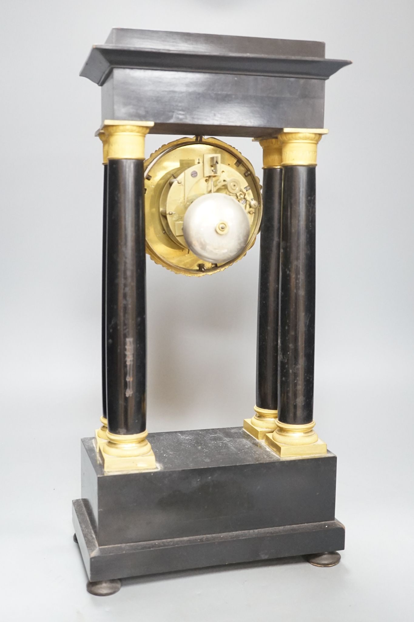 A 19th century French ebonised portico mantel clock with brass mounts, 47 cms high.